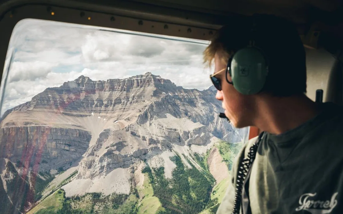 A passenger looking out over the Canadian Rockies from a helicopter