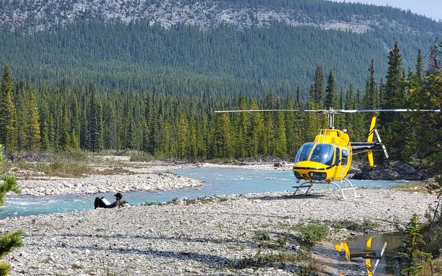 A helicopter landed beside a river in the Canadian Rockies